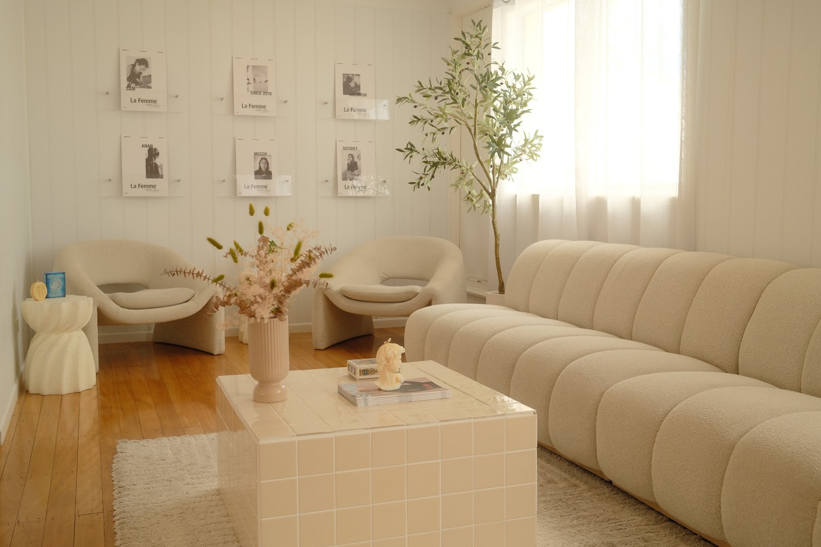 The lounge at La Femme: a curved cream sofa, boucle chairs, a tiled coffee table and artist posters on the wall