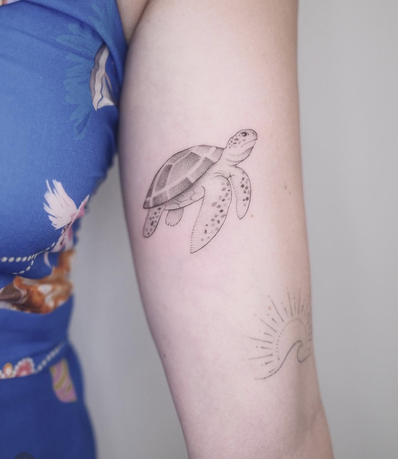 Fine line sea turtle and a small sun over waves on an arm