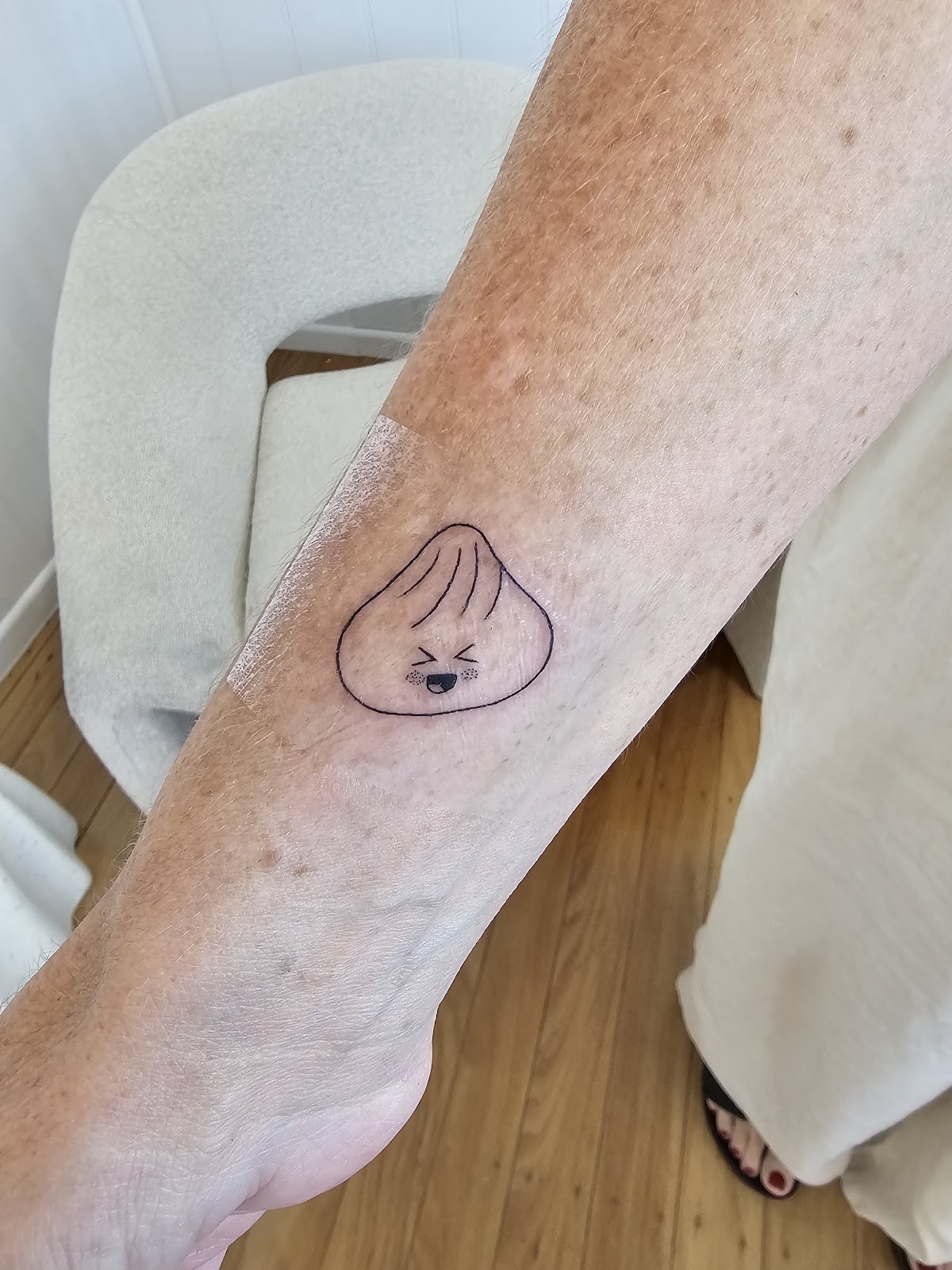 Small smiling dumpling tattoo on an ankle